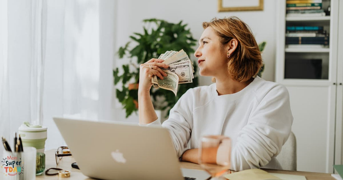 Femme travailleuse indépendante souriante tenant des billets devant son ordinateur portable