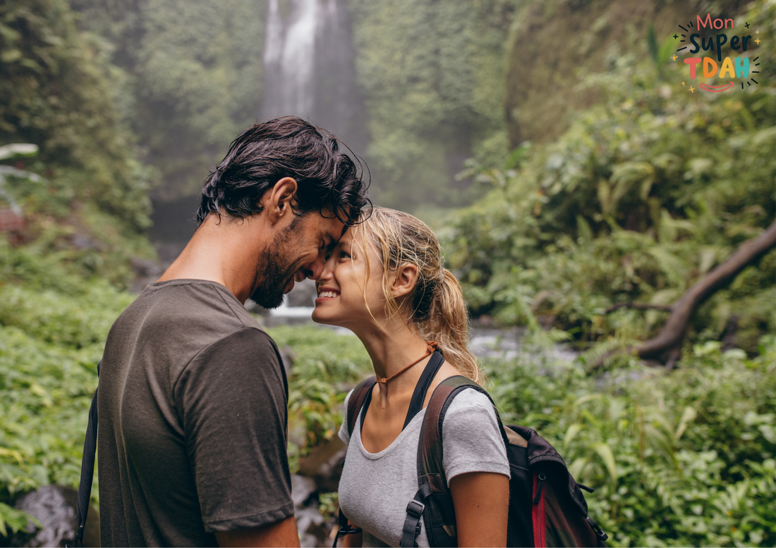 Couple souriant, front contre front, devant une cascade en pleine nature