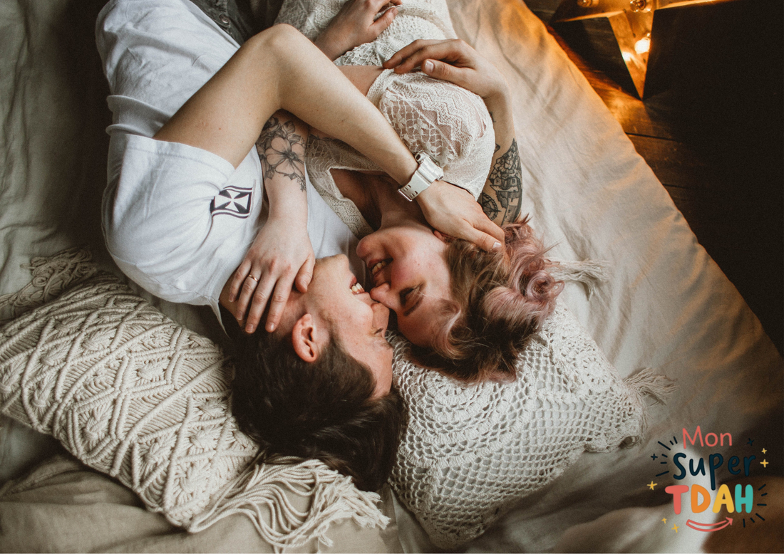 Couple allongé, enlacé et souriant, dans une ambiance chaleureuse et tamisée