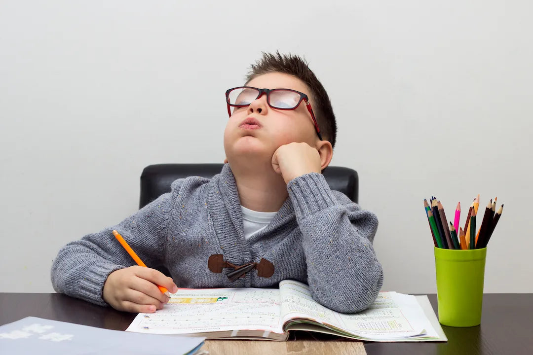 Enfant qui fait ses devoirs mais qui perd la concentration
