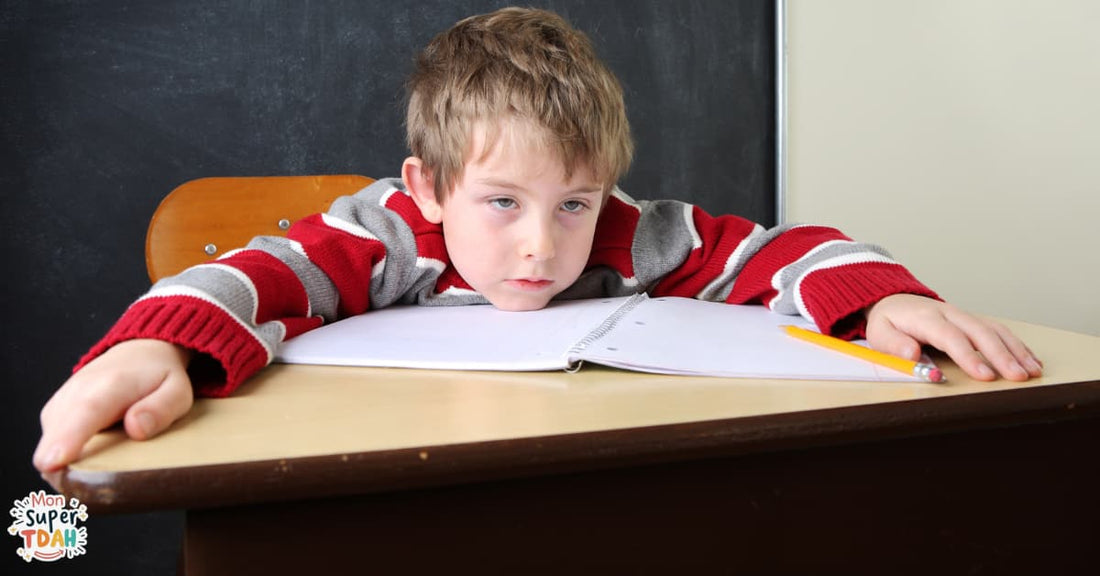 Enfant fatigué, tête posée sur son bureau d'école devant un cahier ouvert