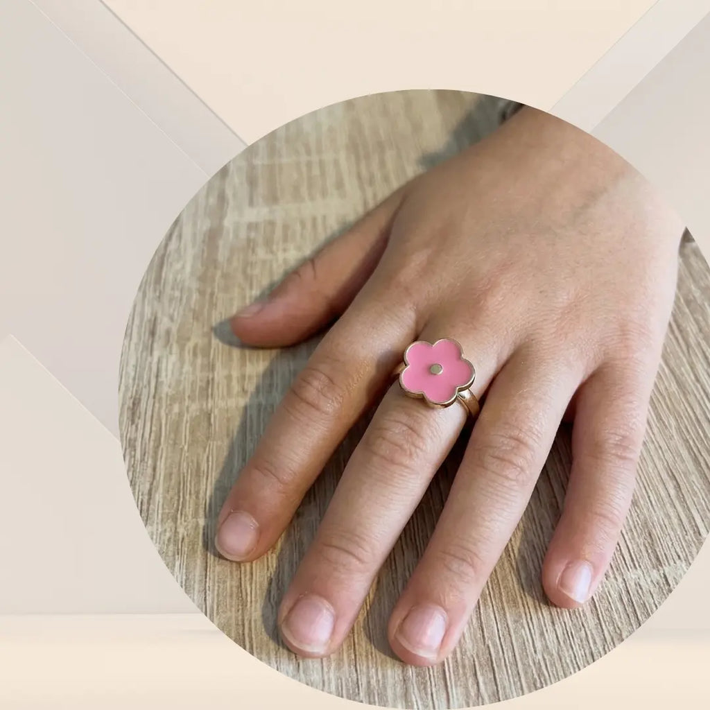 Bague, fleurs roses, antistress sur le doigt d'une petite fille