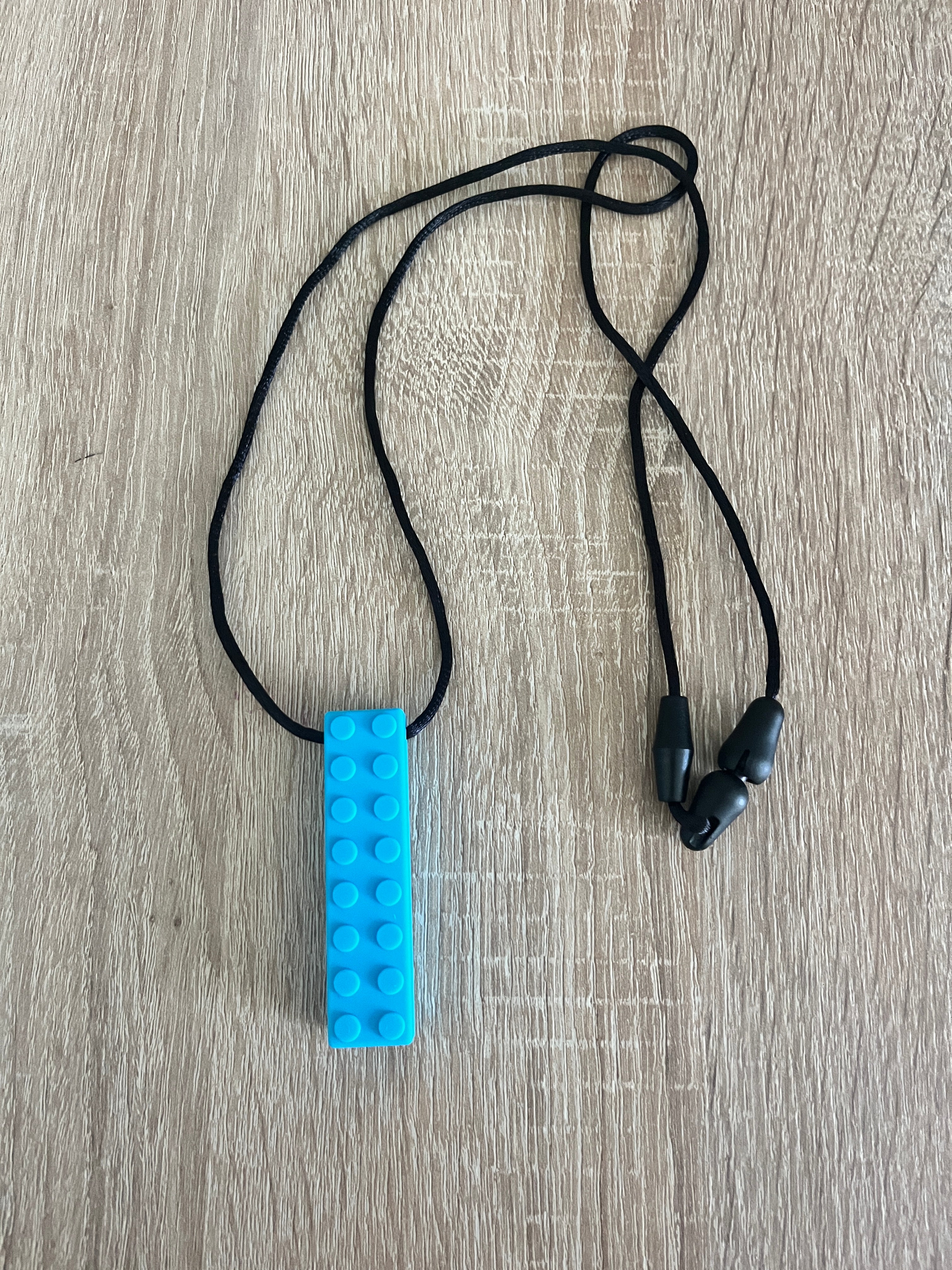 Collier à mâcher type Lego pour enfant de couleur bleu clair – outil d’apaisement et de concentration – visuel présentation produit Mon Super TDAH